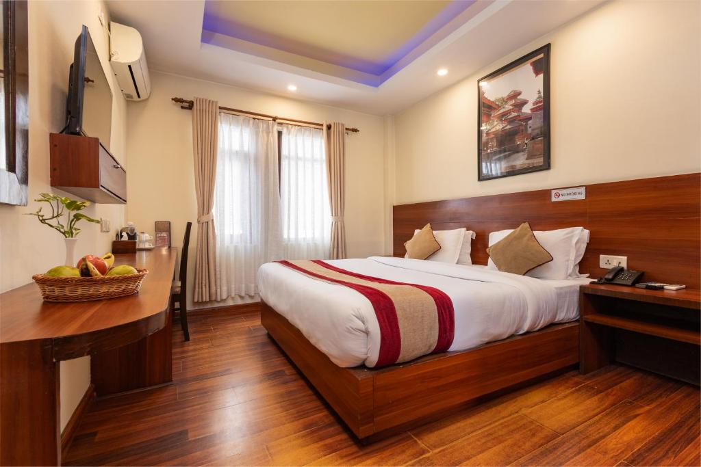 a hotel room with a large bed and a desk at Aryatara Kathmandu Hotel in Kathmandu