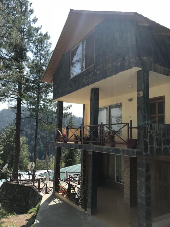 a house with a porch and a balcony at The Cozy Cottage, Dunga Gali in Dunga Gali