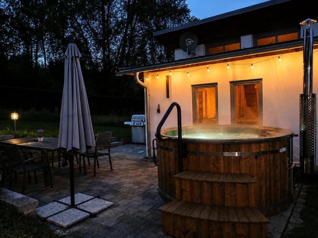 a hot tub in front of a house with an umbrella at Haus im Grünen l Hot Tub l aktivCARD inklusive in Regen