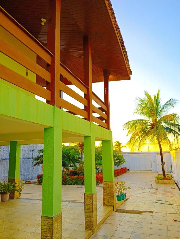 a large wooden chair on a patio with a palm tree at Araçagy Casa Mar in São José de Ribamar