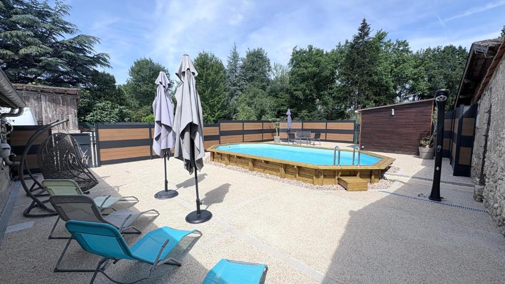 a swimming pool with chairs and umbrellas in a patio at Chambres et Gîtes Les Deux Chênes près de Bergerac in Le Fleix