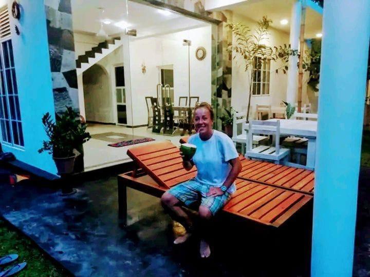 a man sitting on a bench on a patio at Villa Akeinya in Matara
