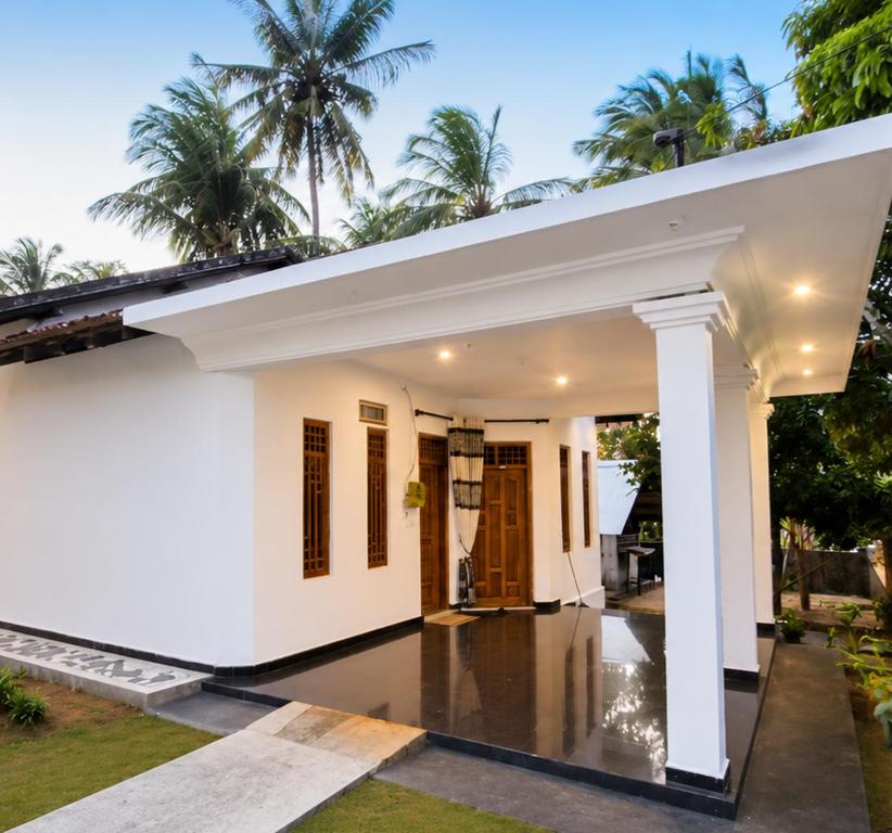 a white house with palm trees in the background at Queens luma villa in Arugam Bay