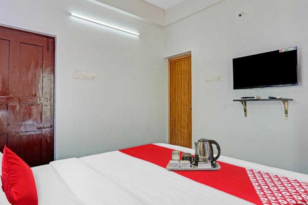a bedroom with a bed with a red and white blanket at Hotel O Bevis in Trivandrum