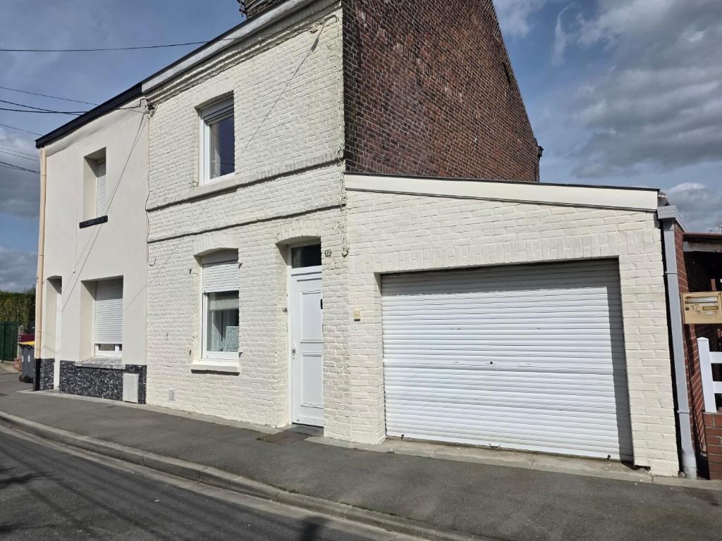 a white brick building with a large garage at maison de madame De souter in Sequedin