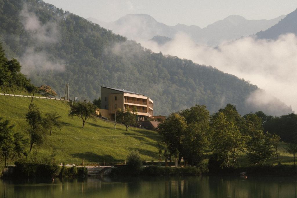 a building on a hill next to a body of water at Hotel Tulie in Most na Soči