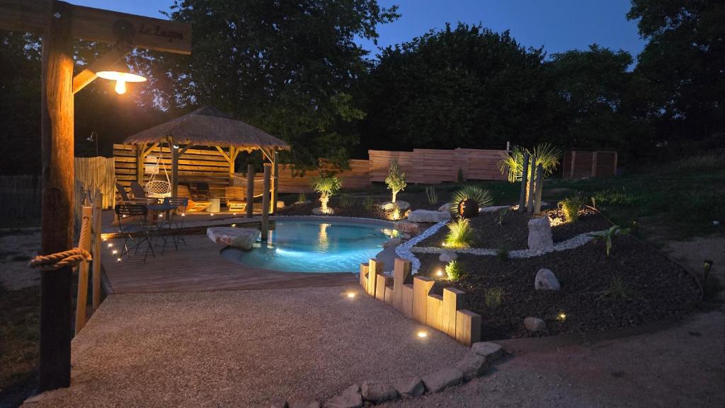 a backyard with a pool and a gazebo at night at Tiny House chez Lili in Frémifontaine