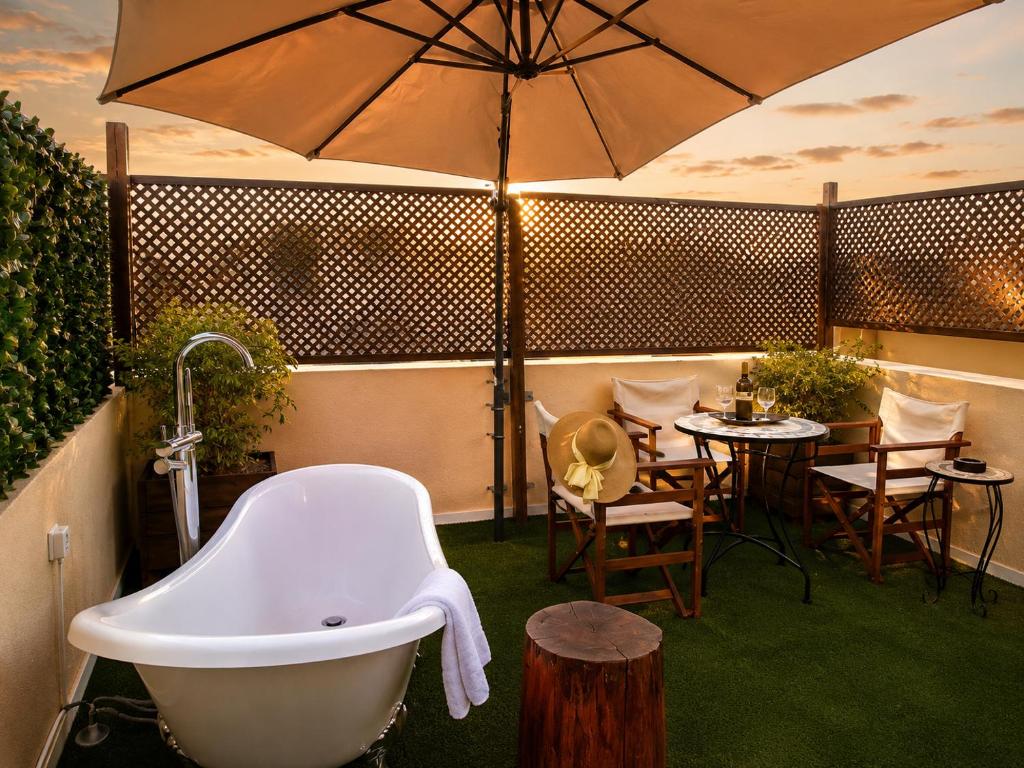 a bath tub sitting next to a table with an umbrella at Old Town Rhapsody, Cosy 2-Floor Home with Rooftop Bathtub, BBQ & Lounge Under Sun Umbrellas in Rethymno