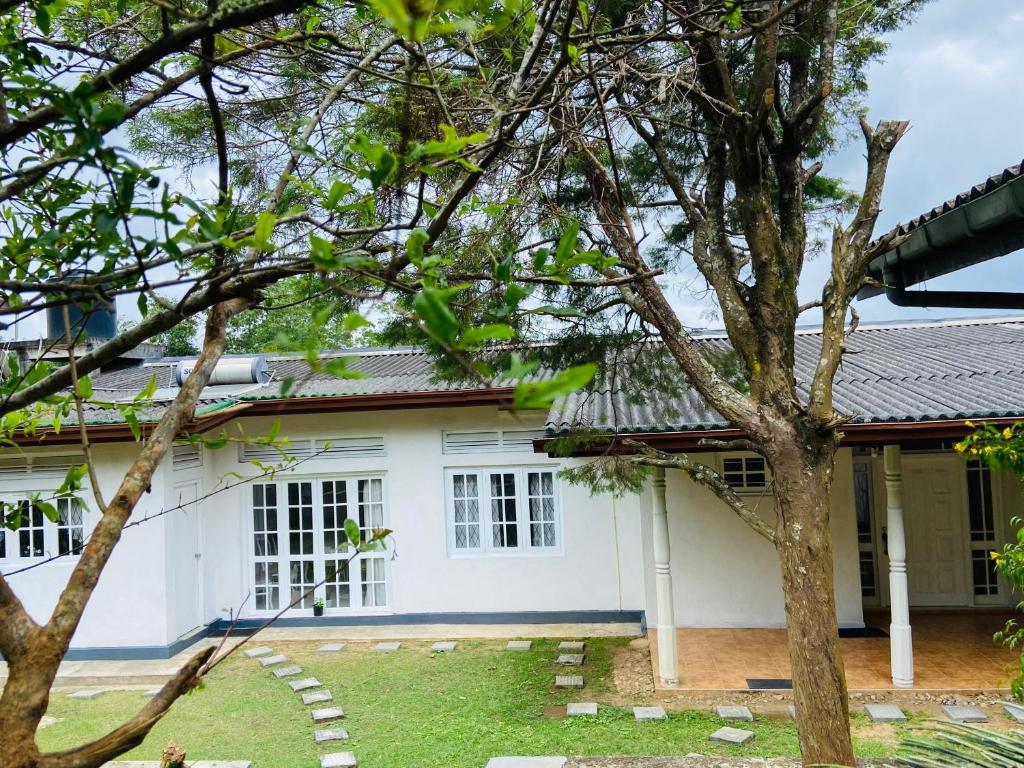 a white house with a tree in front of it at Mountain Breeze Uplands in Kandy