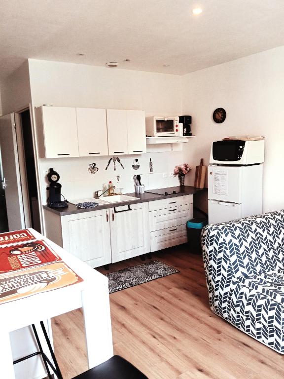 a kitchen with white cabinets and a white refrigerator at T2 Cosy, agréable fonctionnel et douillet, 1 lit 140 et un BZ , Wifi gratuit, boîte à clés, proche commerces et gare routière, linge de lit et toilette offerts à partir de 4 nuits in Graulhet