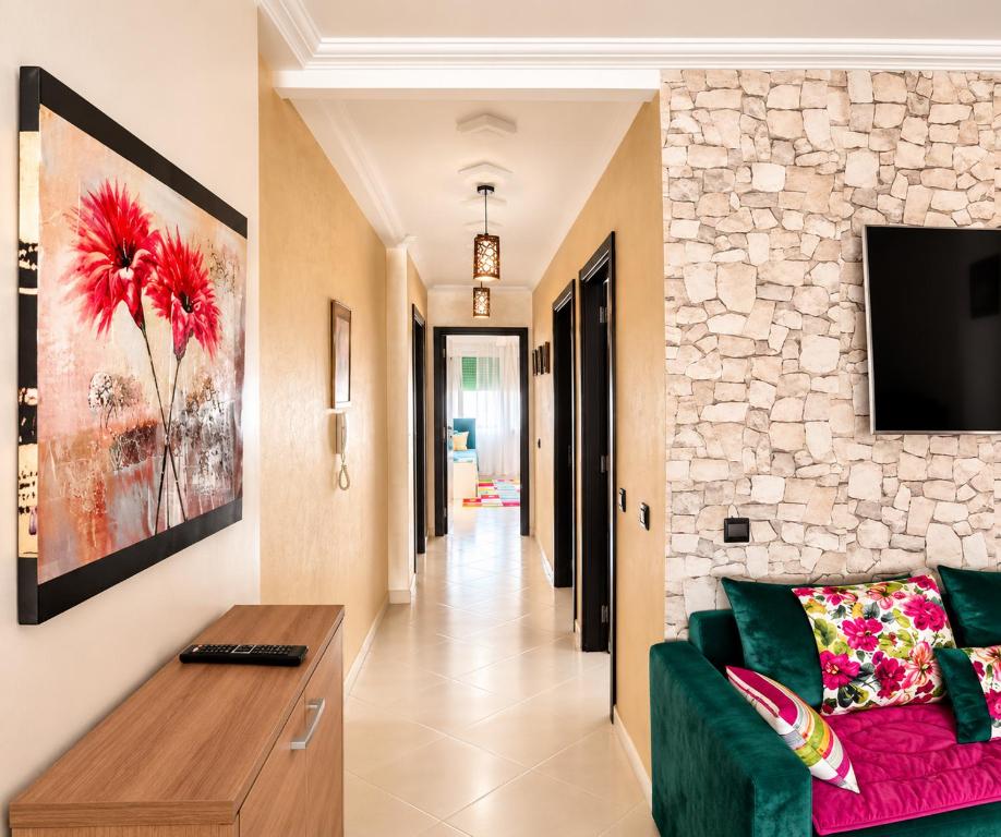 a living room with a green couch and a stone wall at Stylish and valm appartement in Kenitra