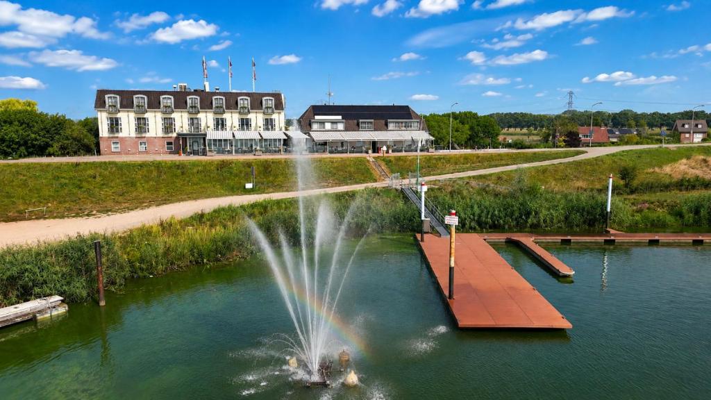 a fountain in a pond with a building in the background at Hotel Hoogeerd by Flow Niftrik - Nijmegen in Niftrik