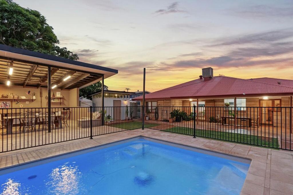 a house with a swimming pool in front of a fence at Dune Break in Exmouth