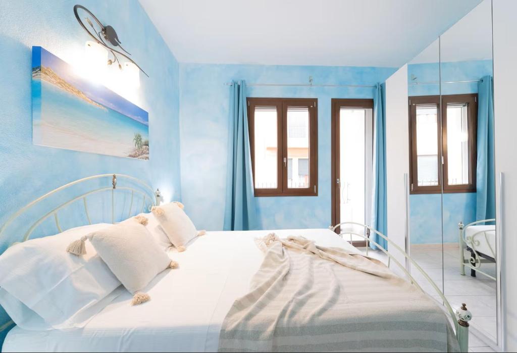 a bedroom with a white bed with blue walls at Bidderosa in Orosei