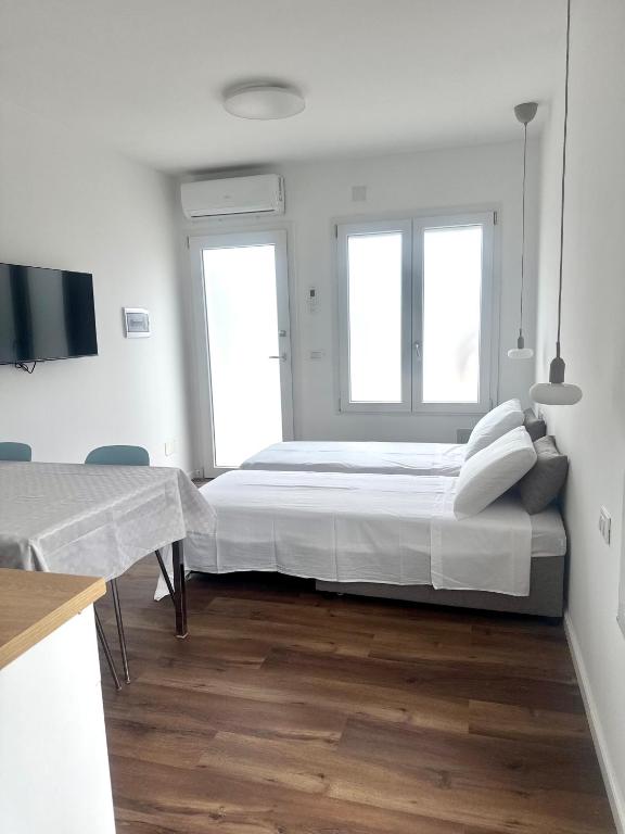 a white bedroom with a large bed and two windows at Arcimboldo 1 apartment in San Canzian dʼlsonzo