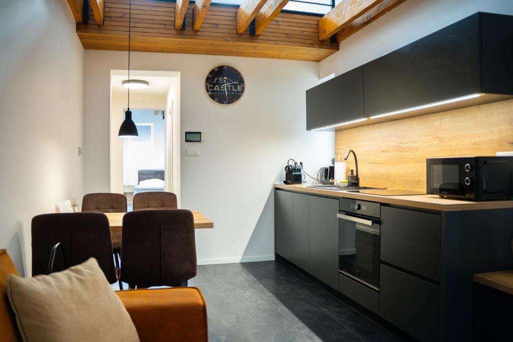 a kitchen with black cabinets and a table with chairs at CASTLE apartments Premium - City Center in Spišské Podhradie