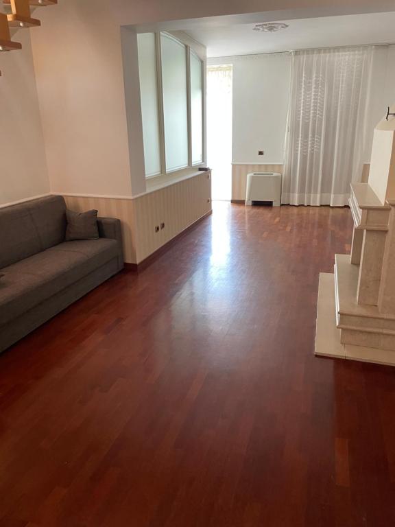 an empty living room with a couch and wooden floors at la Dimora del centro di zafferana in Zafferana Etnea