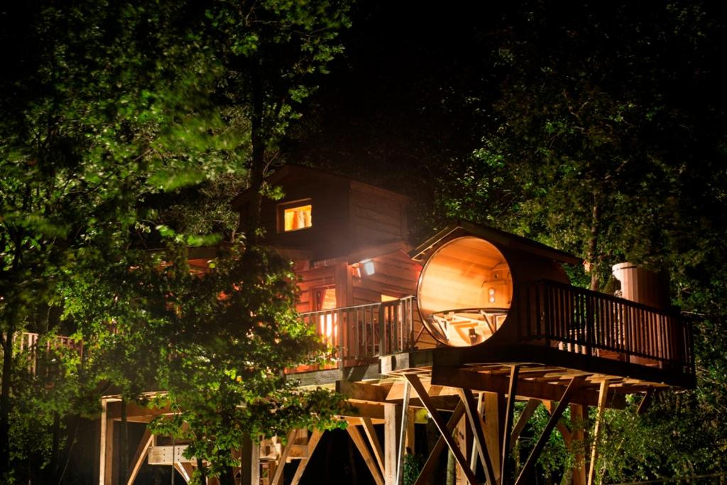 a tree house in front of a building at night at Cabane du Bois des Nauzes in Seyches