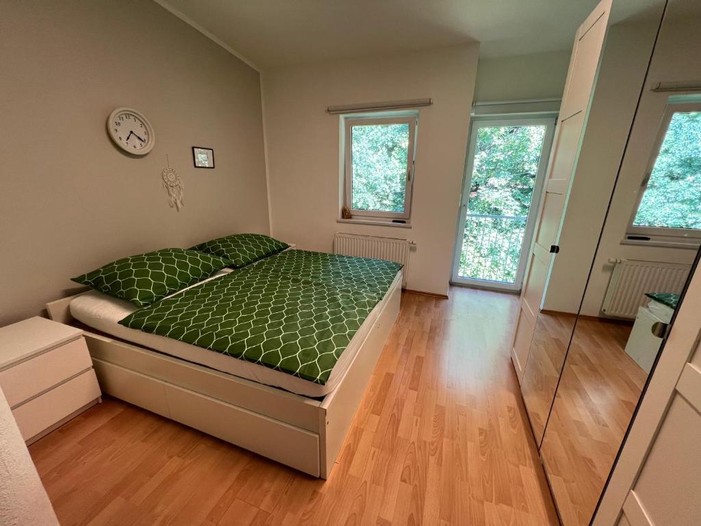 a bedroom with a bed with green sheets and two windows at LH Rooms in Absam