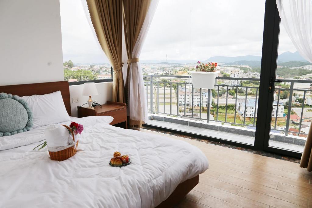 a bedroom with a white bed with a large window at Enjoy Villa Da Lat in Khu Chi Lăng
