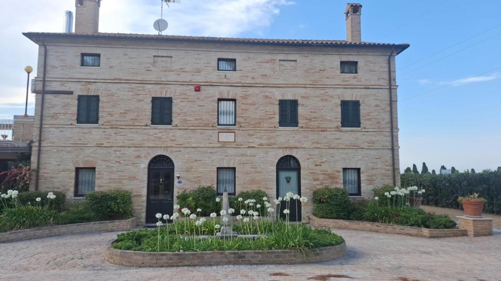a large brick building with white flowers in front of it at Hotel Villa Fanti in Loreto