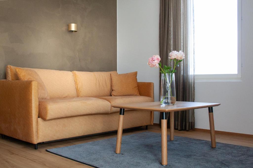 a living room with a couch and a table with flowers at Ski-Inn Huoneisto in Vuokatti