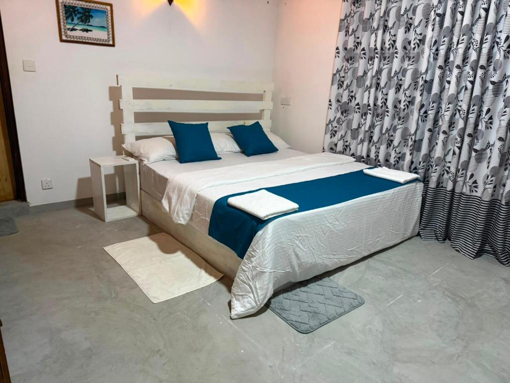 a bedroom with a large bed with blue pillows at Green Villa Midigama in Midigama East