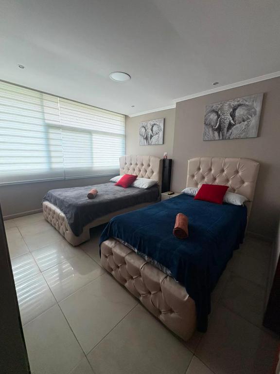 a bedroom with two beds and a couch at Departamento 68 river 2 in Guayaquil