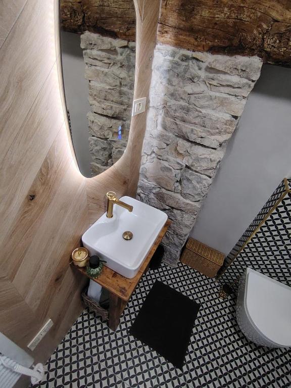 a bathroom with a sink and a stone wall at VODIČARJEVA HiŠiCA in Grgar