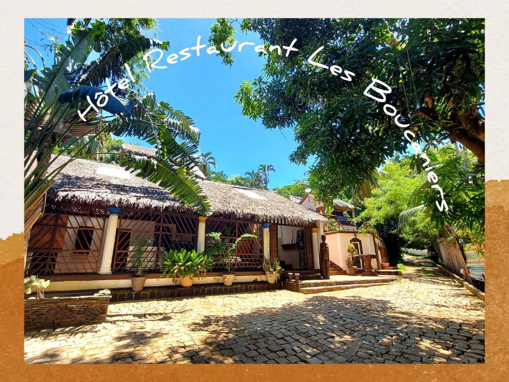 a house with a thatch roof and a driveway at Hotel Les Boucaniers in Ambatoloaka