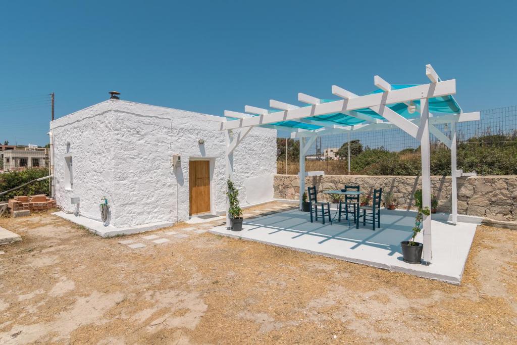 a white house with a pergola and a table and chairs at Paraspori in Adamantas