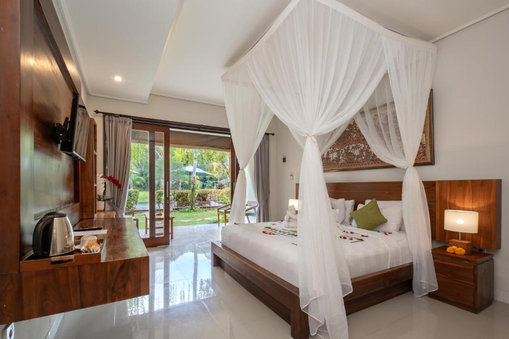 a bedroom with a canopy bed with white drapes at Ubud Tropical Garden in Ubud