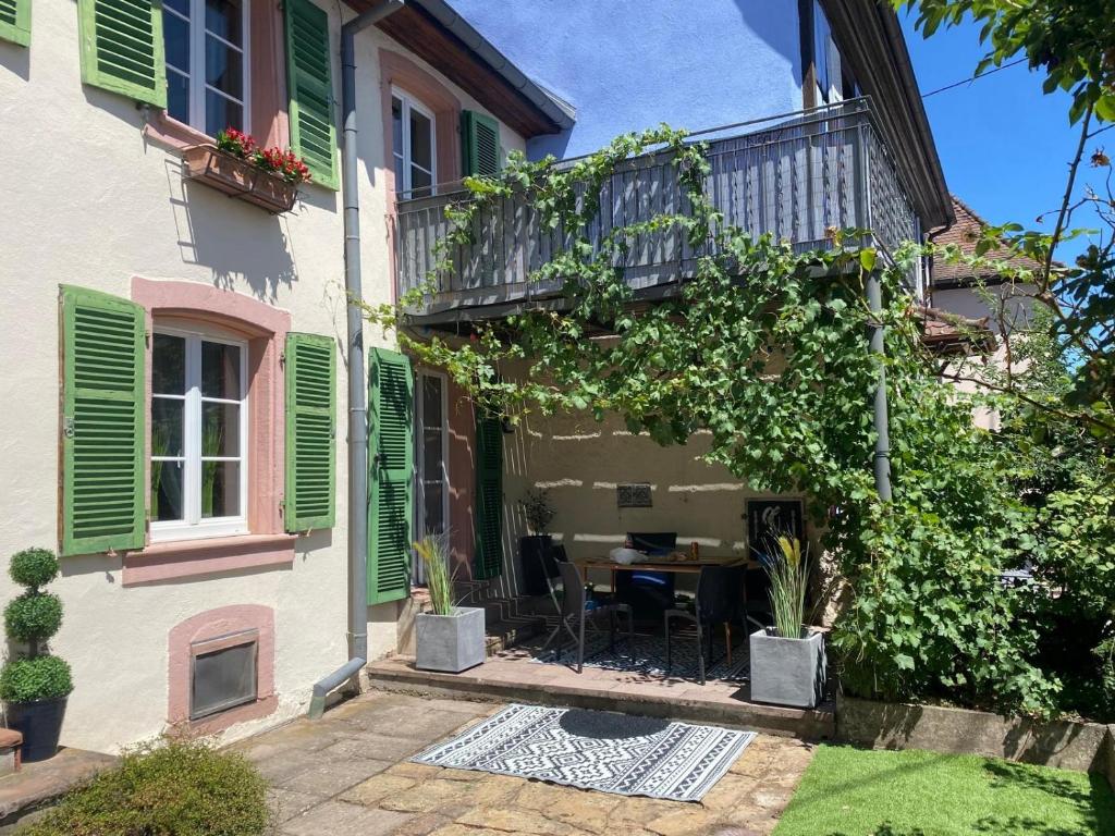 a house with a balcony and a table in the courtyard at Maison HELIOS - Eguisheim in Eguisheim