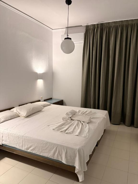 a bedroom with a white bed and a window at Skala Apartments in Agia Marina Nea Kydonias