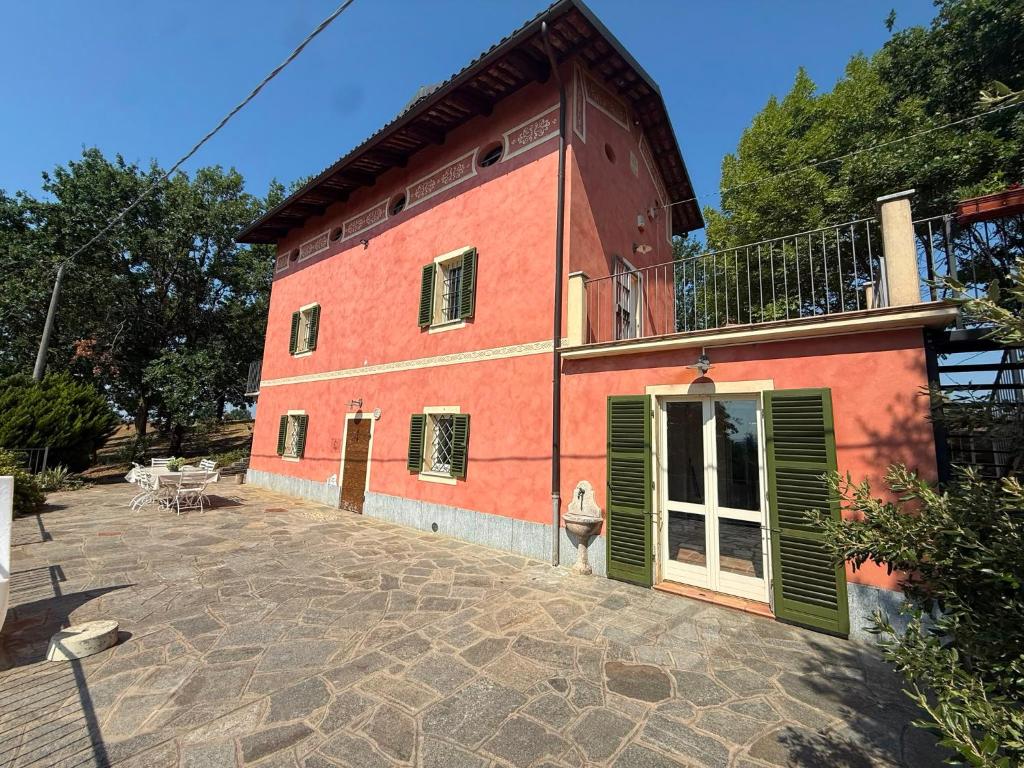 a large red building with a balcony and a patio at Casia Vacanze con due appartamenti in Bene Vagienna