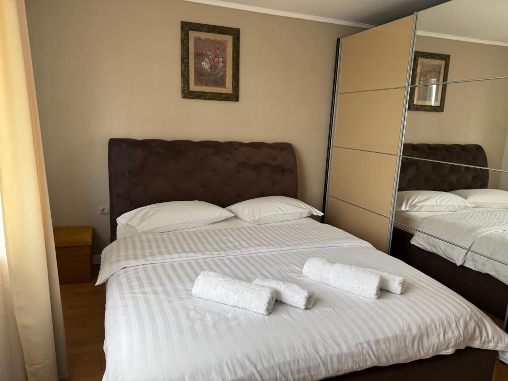 a bedroom with two beds with white sheets and mirrors at Casa Larisa Borsa in Borsa