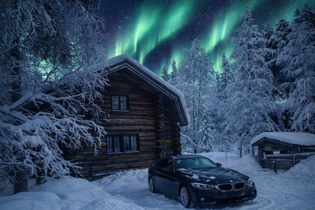 a car parked in front of a cabin with the northern lights at Villa Pukelo Arctic Lodge with wifi sauna 4 poster bed fireplace in Salla