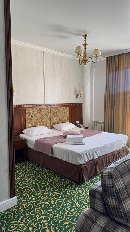 a bedroom with a large bed and a chair at Белес in Astana