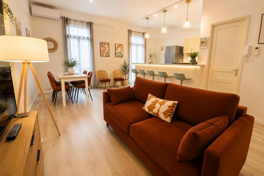 a living room with a brown couch and a kitchen at Gare - Spacieux T2 avec Clim Balcon Wifi in Perpignan