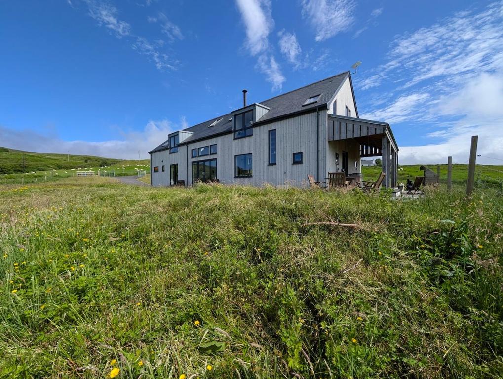 a large white building in a field of grass at Lon Godrum in Kingsburgh