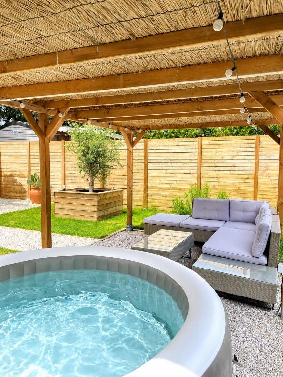 a hot tub in a backyard with a pergola at Le Soléa in Le Cailar