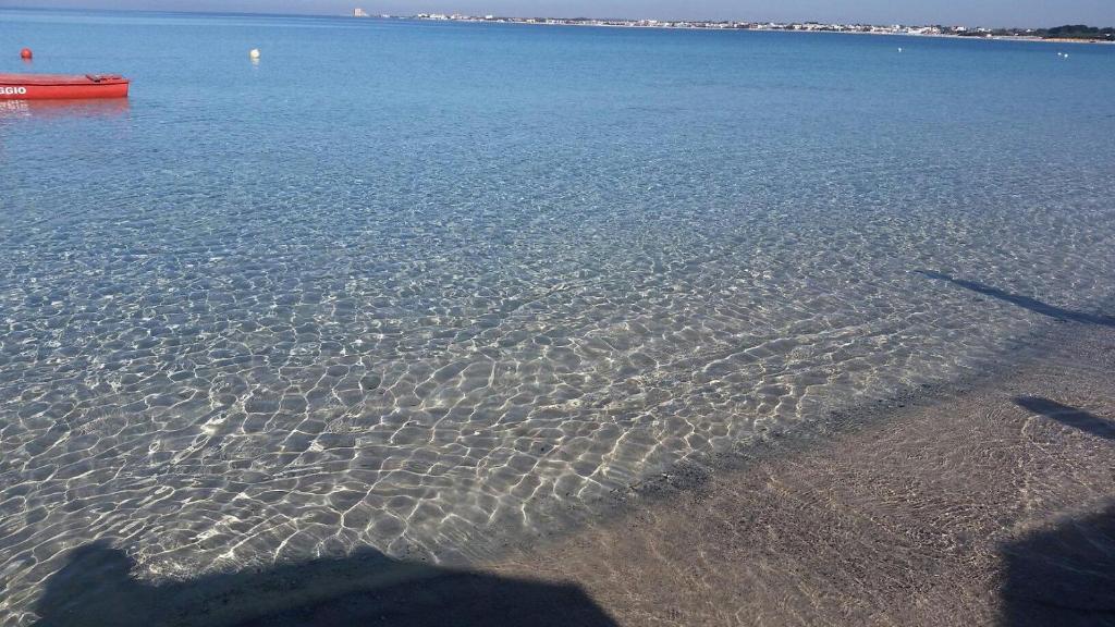 a beach with a red boat in the water at Villa Belvedere Salento in Porto Cesareo