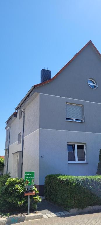 a white building with a green sign in front of it at Ferienwohnung Halberstadt in Halberstadt