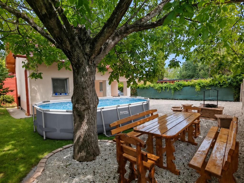 a picnic table and a tree next to a pool at Napsugár Vendégház Velence in Velence