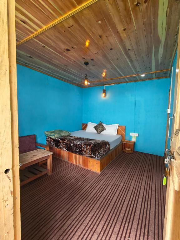 a bedroom with a bed and a blue wall at Pulga Inn in Kalgha