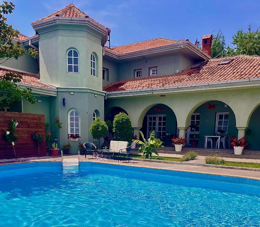 a large house with a swimming pool in front of it at SUNNY HOUSE APARTMENTS WITH an OUTDOOR POOL AND FREE PARKING in Skopje