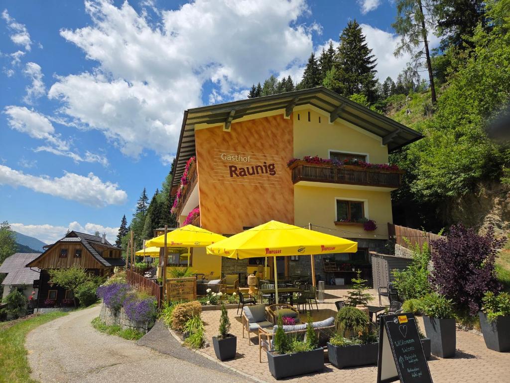 a building with tables and umbrellas in front of it at Hotel Restaurant Raunig in Bad Kleinkirchheim