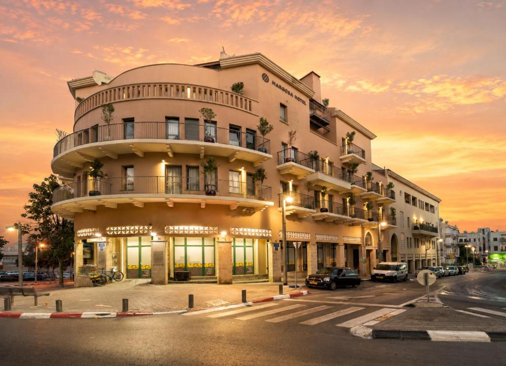 a building on the corner of a street at sunset at Margosa Boutique Hotel Tel-Aviv Jaffa in Tel Aviv