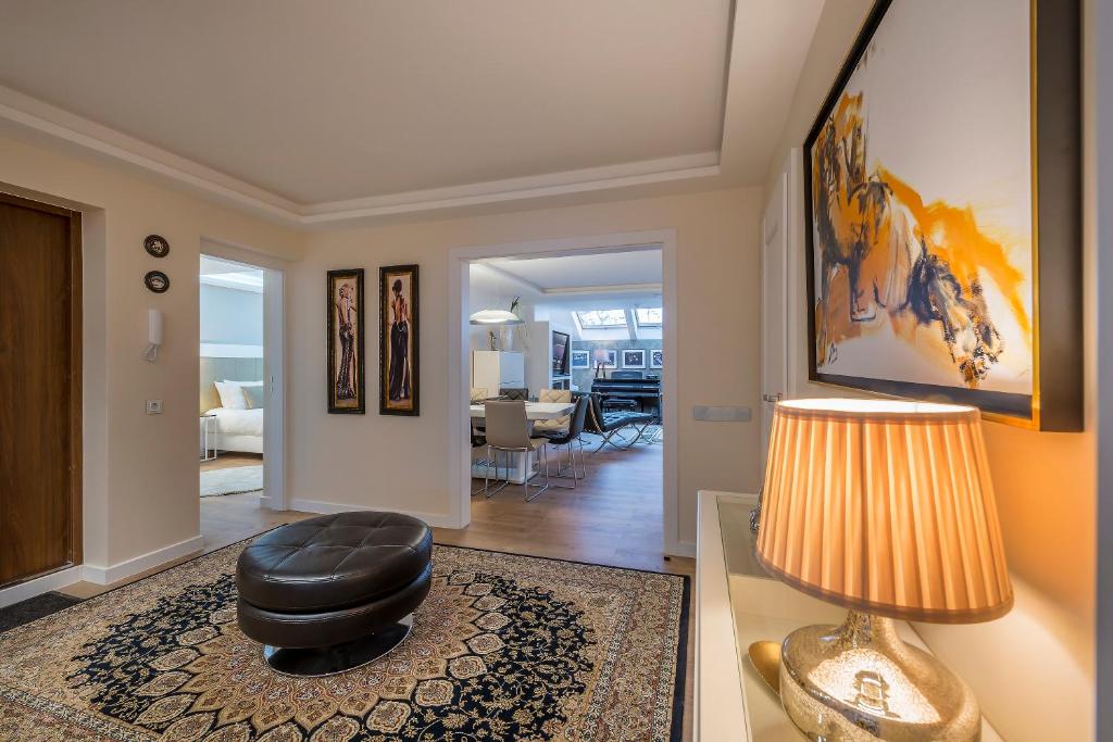 a living room with a ottoman and a table with a lamp at Hills Park Luxury Apartment in Vilnius