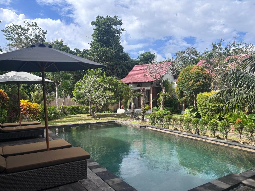 a swimming pool with an umbrella next to a house at Alaksa villa padang padang 6 in Bingin Beach